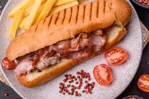Delicious juicy hot dog with sausage, bacon, sauce, salt and spices y photo