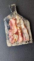 Delicious bacon in the form of slices with salt, spices and herbs on a dark concrete background video