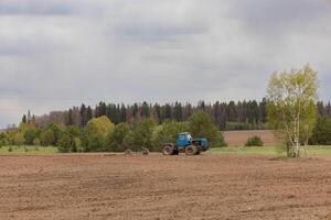 A farmer on a tractor plows a field in the spring photo