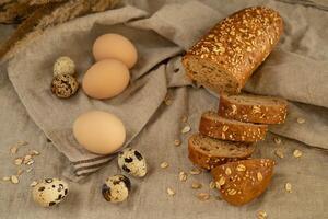 Smooth cereal baguette with sunflower seeds, chicken eggs and quail natural fresh farm eggs on a linen towel photo