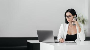 Confident hispanic businesswoman in glasses working on laptop at her workplace at modern office against white background. 30s middle female using computer technology app for work online. Copy space photo