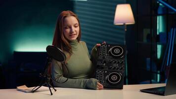 Cheerful girl mixing on DJ turntables, doing music production tutorial for online streaming channel. Smiling young content creator playing around with stereo sound mixer, camera A video