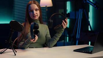 Gen Z influencer in home studio films headphones comparison for audience, recording with professional microphone to accurately capture sound, hosting technology internet show for fans, camera A video