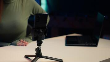 Focus on mobile phone used by influencer to film content for her online fans, talking about gen Z topics. Content creator records vlog for internet channel with cellphone on tripod, camera A close up video