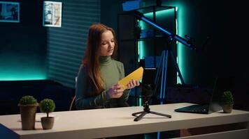 Young influencer filming review of light bulb able to change into different colors. Content creator showcasing smart home automation technology in apartment studio, camera B video
