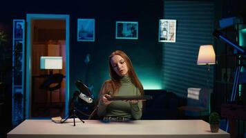 Young entertainer presenting sleek laptop from brand sponsoring , urging viewers to purchase it. Girl does influencer marketing by advertising thin notebook to audience in studio, camera B video
