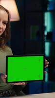 Vertical Happy teenager presenting mockup tablet in entry level low budget price range for tech enthusiasts. Jolly gen Z influencer reviewing isolated screen device in front of internet subscribers video