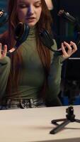 Vertikale Internet Show Gastgeber halten Paar von teuer Kopfhörer im Hände, tun hergeben zum treu Zuschauer, filmen mit Telefon. Mädchen Hosting online Wettbewerb zum Fans mit Audio- Technik wie Preis, Kamera ein video