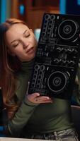 Vertical Gen Z artist mixing on DJ turntables, doing music production tutorial for internet streaming channel. Teenage media star playing around with stereo sound mixer in home studio, camera A video