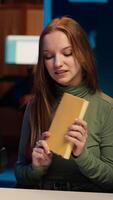 Vertical Young content creator films review of book, browsing through pages, presenting synopsis to audience. Internet star sponsored by publisher to show new novel release to readers, camera A video