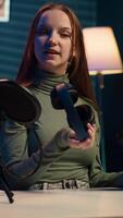 Vertical Content creator filming herself listening to new album from favorite artist, reviewing music. Online star hosts internet show, rating songs, hearing them through noise cancelling headphones, camera A video
