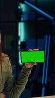 Vertical Smiling tech expert reviews newly released mockup green screen smartphone, comparing features with older models. Upbeat influencer analyzing latest generation of chroma key mobile phone video