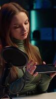 Vertical Tech specialist filming technology review of newly launched smartphone, presenting features to subscribers. Influencer advertising mobile phone to fans from home studio, camera A video