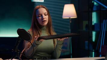 Entertainer presents keyboard and mouse from brand sponsoring , urging viewers to buy it. Young girl does influencer marketing by advertising computer peripherals to audience in studio, camera A video