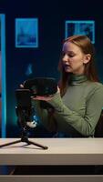 Vertical Gen Z tech expert filming sponsored content, unboxing newly released VR glasses product to make viewers buy it. Influencer presenting virtual reality headset product to audience, camera B video