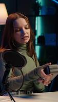 Vertical Gen Z media star filming about best bluetooth music playing devices of the year. Happy young tech content creator recording portable speaker review, evaluating audio quality, camera A video