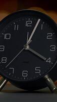A sleek and modern black alarm clock resting elegantly on a wellorganized table surface video
