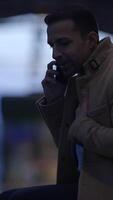 A man is seen talking on his phone in the dim light, creating an intriguing atmosphere video