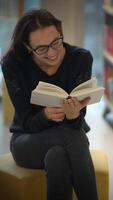 A Joyful Reader Delightfully Enjoying a Book while Seated Comfortably in a Cozy Library video