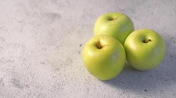 Three organic green golden apples rotating on gray cement background. Golden Apples on gray background rotation. Copy space for text. Food HD. video