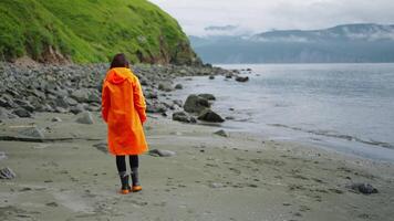 Lonely Woman In Orange Raincoat Walking On Coast Of Ocean Or River In Beautiful Touristic Place video