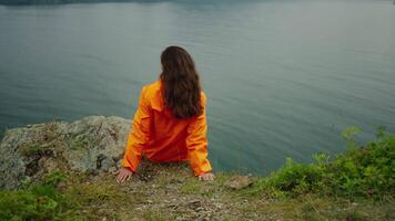 Back View Of Female Tourist Sitting On Edge Of Cliff On Ocean Coastline, Admiring Beautiful Gulf video
