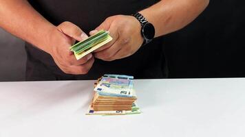A person is meticulously sorting euro bills into neat stacks on a table, focusing on organization and currency management while ensuring accurate counts video