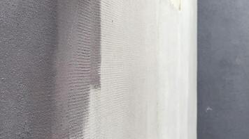 A hand is skillfully applying a quartz wall finish using a brush, creating a smooth and even texture on the wall during home renovation work video