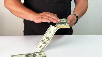 A hand gently hovers over sliding bills on a flat surface, giving a sense of action and movement. The focus is on the transition of money, emphasizing dynamics in a simple backdrop video