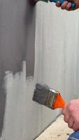 A person demonstrates wall painting techniques using two brushes to apply gray paint, focusing on achieving a smooth finish on the surface video