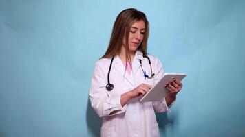 Woman doctor using digital tablet on light blue background video