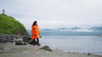 Picturesque Landscape With Ocean And Mountains In Kamchatka And Woman Tourist In Raincoat Walking video