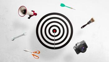 Black-and-white target surrounded by a megaphone, dart, paintbrush, camera, scissors, and wrench, symbolizing a marketing campaign and creative goal-oriented activities photo