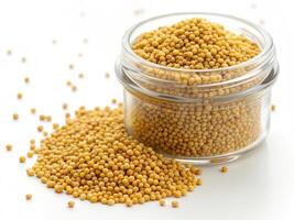 small heap of bright yellow mustard seeds in glass jar photo