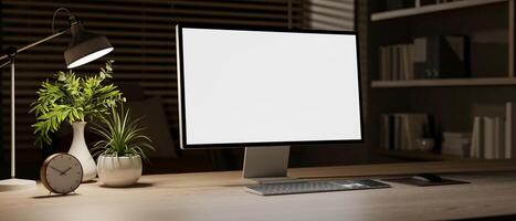 A close-up of a computer with a white screen mockup on a wooden desk in a room at night. photo