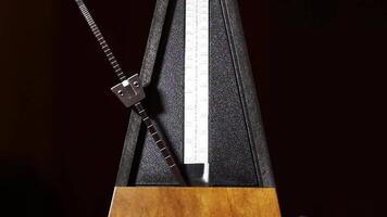 Tight Shot Of Moving Arm On Mechanical Metronome With Dark Background video