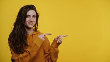 Smiling Woman Pointing to the Side on Yellow Background video