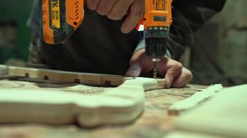 A woodworking carpenter saws off a board with a hand saw. The process of processing wooden boards in a workshop for making solid wood furniture. An experienced carpenter is in an authentic workshop. High quality 4k footage video