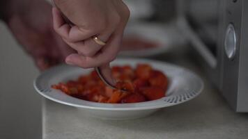 Red strawberry berry in a plate. A man's hand kneads strawberries with a fork in a plate to the consistency of mashed potatoes. video