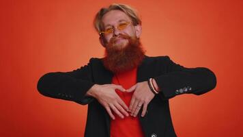 Smiling redhead man makes heart gesture demonstrates love sign expresses good feelings and sympathy video