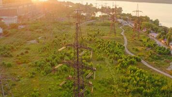 Power line pylons near the river. Electric towers with electric cables with high voltage current. Flight over the transmission lines in the evening. Aerial view. video