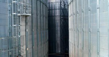Large metal silo for storing grain. Modern industrial plant. Granary. Silver containers storing agriculture crop. Grain elevators on nature background. Close-up. Motion up. video