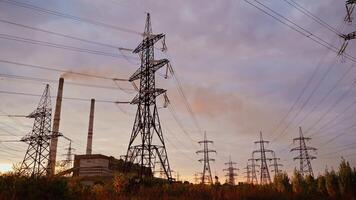 High-voltage electric towers at sunset. Transmission lines on field on the evening sky background. Electricity distribution. View from below. video