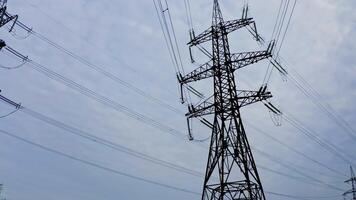 High electric towers with wires. Power transmission pylons under the light sky. Electricity distribution station. View from below. video