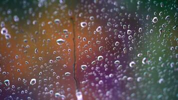 Droplets on colorful background. Raindrops flow down the glass window. Drops of water falls into the window. Close-up. video