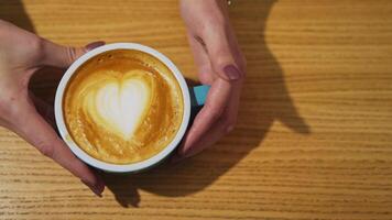 Serving a cup of hot drink. Heart design from milk on coffee. Cup of coffee with latte art in a form of a heart on a wooden background. Close-up. video