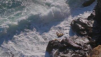 the sea waves crash on the rocks of the coast creating an explosion of water. Breathtaking top aerial slow motion view video