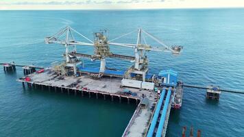 An aerial shot showcasing a state-of-the-art bulk material handling system at a busy coastal port. The image highlights the complex infrastructure involved in maritime shipping and logistics. video