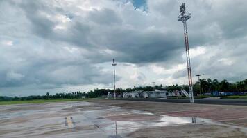 This image depicts a vast, empty airport runway under a dramatic, cloudy sky. The tarmac stretches out, reflecting the ominous clouds above, creating a serene and melancholic atmosphere. video