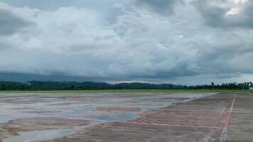 This footagedepicts a vast, empty airport runway under a dramatic, cloudy sky. The tarmac stretches out, reflecting the ominous clouds above, creating a serene and melancholic atmosphere. video